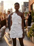 Model wearing the white asymmetrical off-shoulder cocktail dress in an elegant evening setting