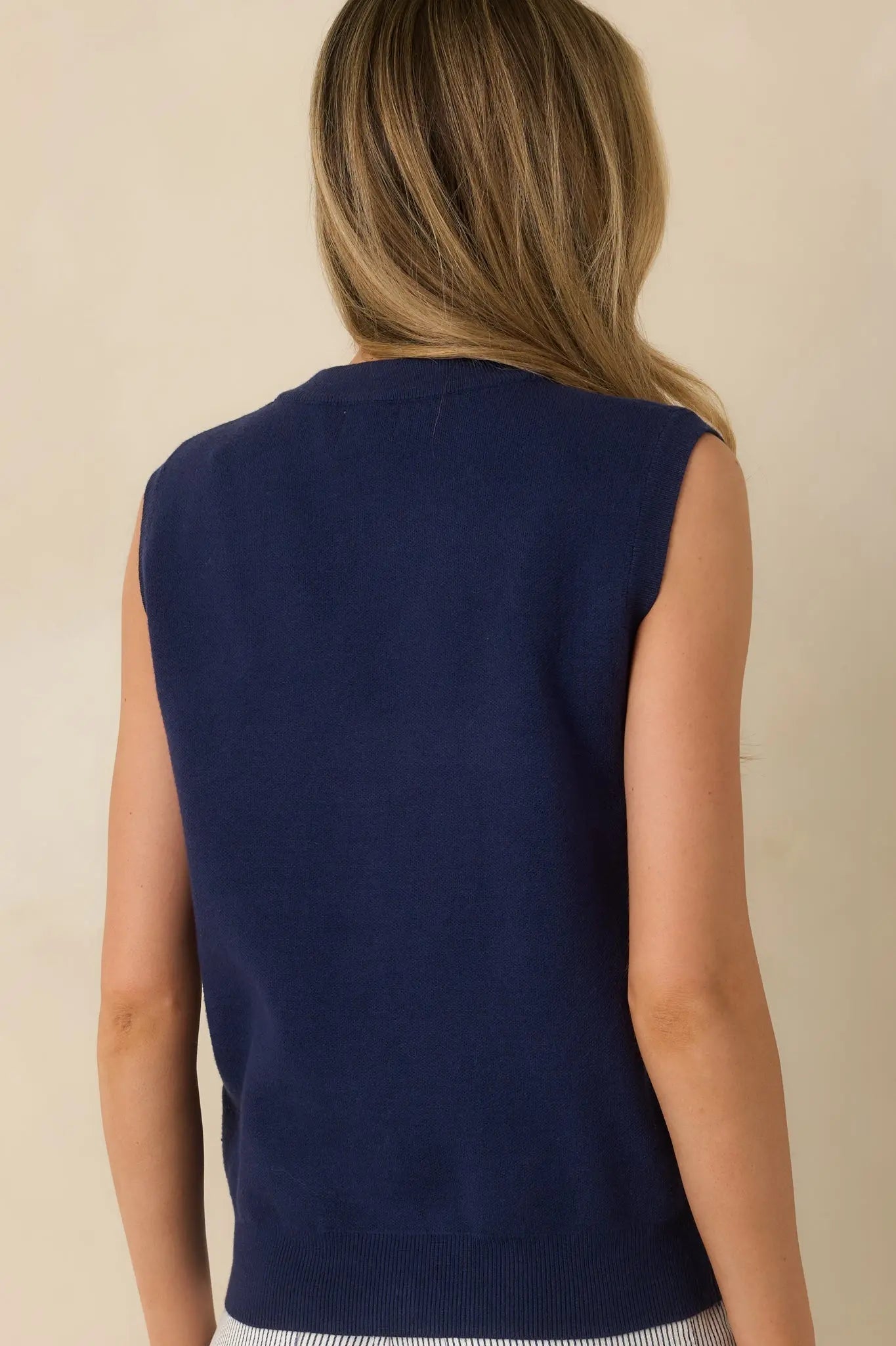Navy blue knit sweater vest with gold shell buttons, full look